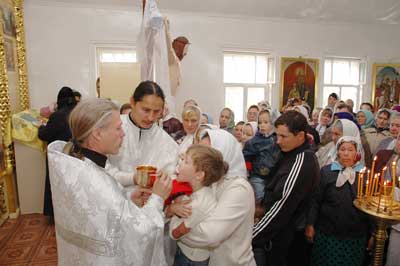 Отец Сергий причащает первых прихожан. Фото Валерия БАКЛАНОВА.